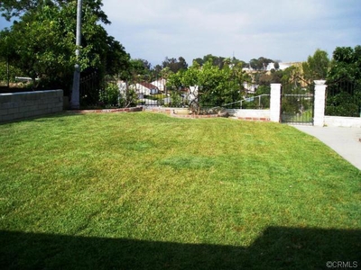 a hill with lots fruit trees behind the gate of the backyard